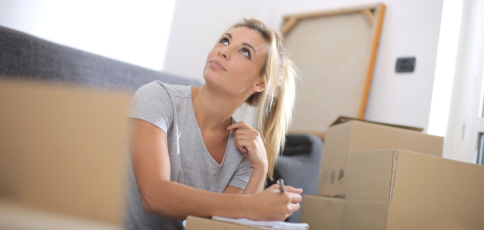 Дівчина готується до переїзду в нове житло, речі зібрані в картонні коробки. Ілюстрація