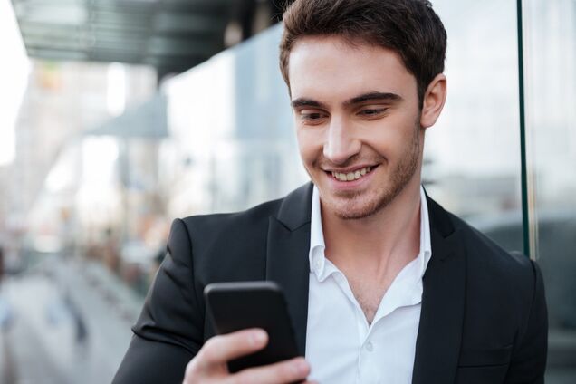 Ілюстрація - молодий бізнесмен дивиться у смартфон