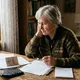 Пенсионерка сидит в квартире с документами, пенсионным удостоверением. Иллюстрация