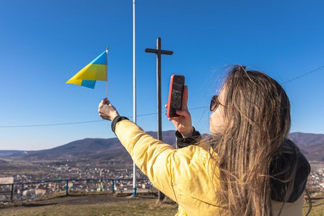 Ілюстрація - жінка фотографує прапорець України