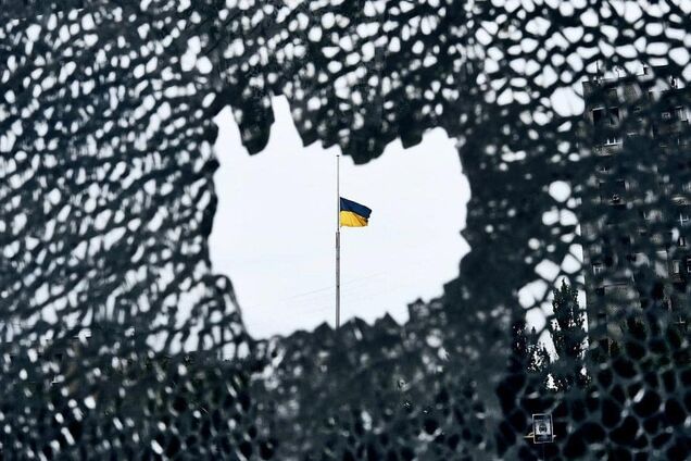Иллюстративное фото. Украинский флаг на фоне маскировочной сетки